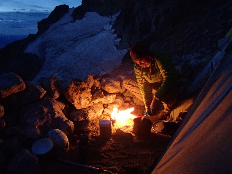 Ernie preparing an eraly morning breakfast with Middle Teton glacier in background